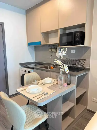 Modern compact kitchen with dining area, featuring sleek cabinetry and integrated appliances.