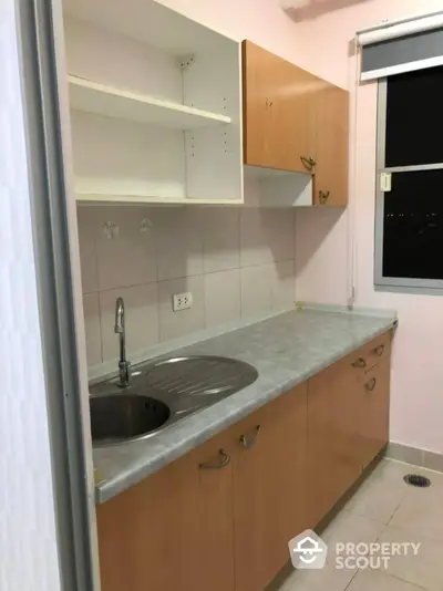 Cozy kitchen with wooden cabinets and stainless steel sink in a compact layout.