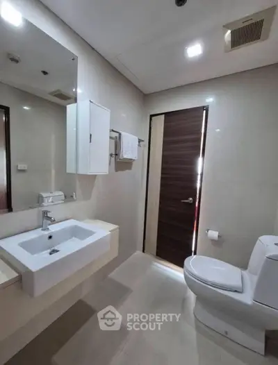 Modern bathroom with sleek fixtures and elegant design, featuring a spacious sink and contemporary toilet.