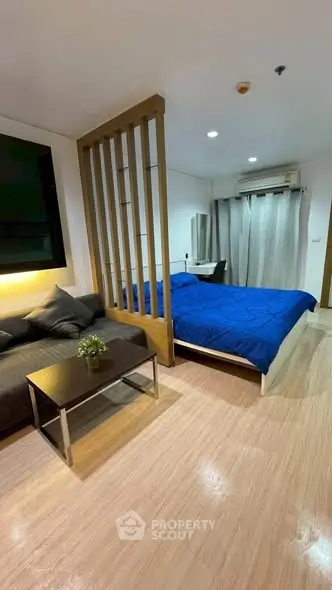 Modern studio apartment with cozy living area and stylish bedroom divider.