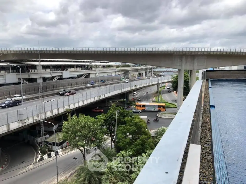 Urban view from a high-rise building with highway and poolside, showcasing city infrastructure and modern living.