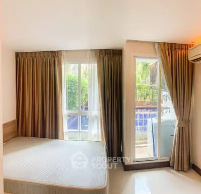 Spacious bedroom with large windows and garden view, featuring air conditioning and modern decor.
