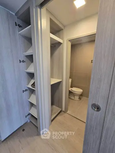 Modern bathroom with sleek storage shelves and wooden flooring, featuring a minimalist design.