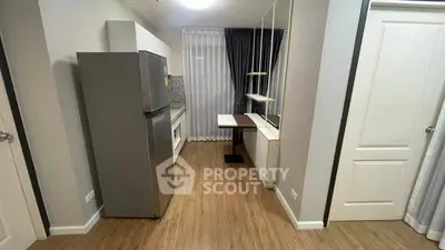 Modern kitchen with sleek design and wooden flooring, featuring a stainless steel fridge and ample storage space.