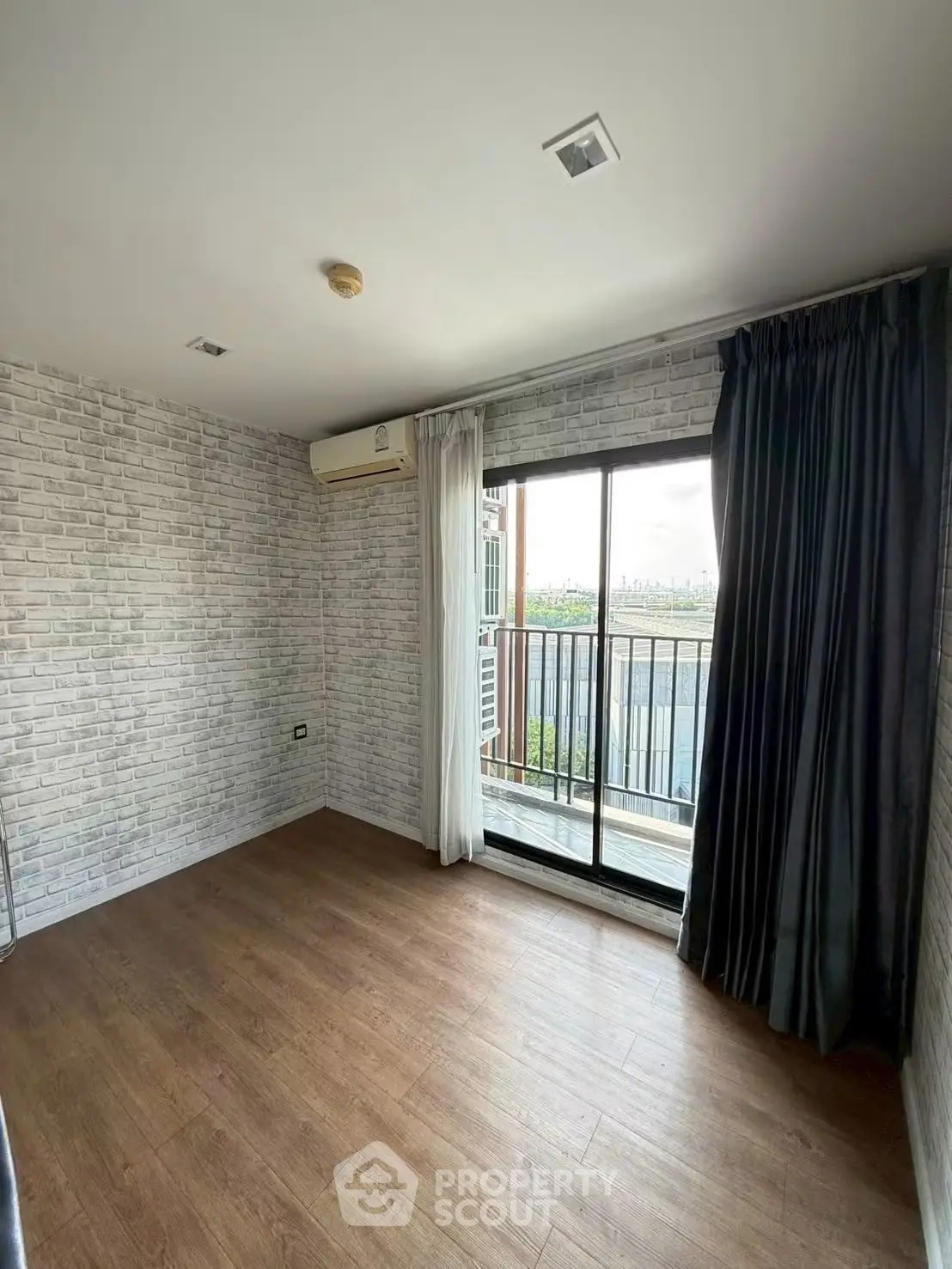 Spacious room with modern brick walls and balcony view, perfect for urban living.