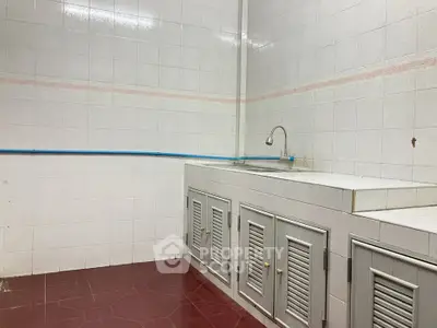 Simple kitchen with tiled walls and basic cabinetry, featuring a single sink.