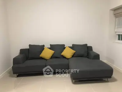 Modern living room with stylish gray sectional sofa and yellow accent pillows