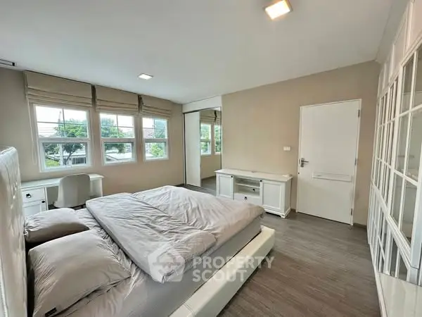 Spacious bedroom with large windows and modern furnishings, offering a bright and inviting atmosphere.