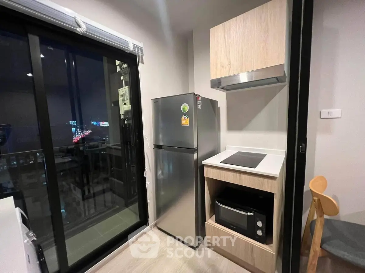 Modern kitchen with sleek appliances and balcony view in urban apartment