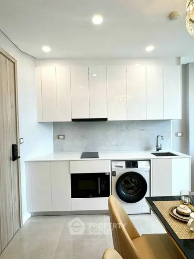 Modern kitchen with sleek white cabinets, built-in appliances, and elegant dining setup.