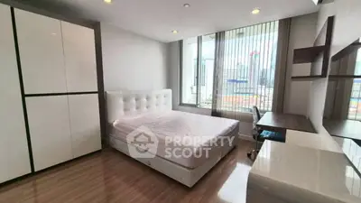 Spacious bedroom with city view, modern furniture, and ample natural light.