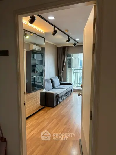 Modern living room with wooden flooring and stylish lighting, featuring a cozy sofa and balcony access.