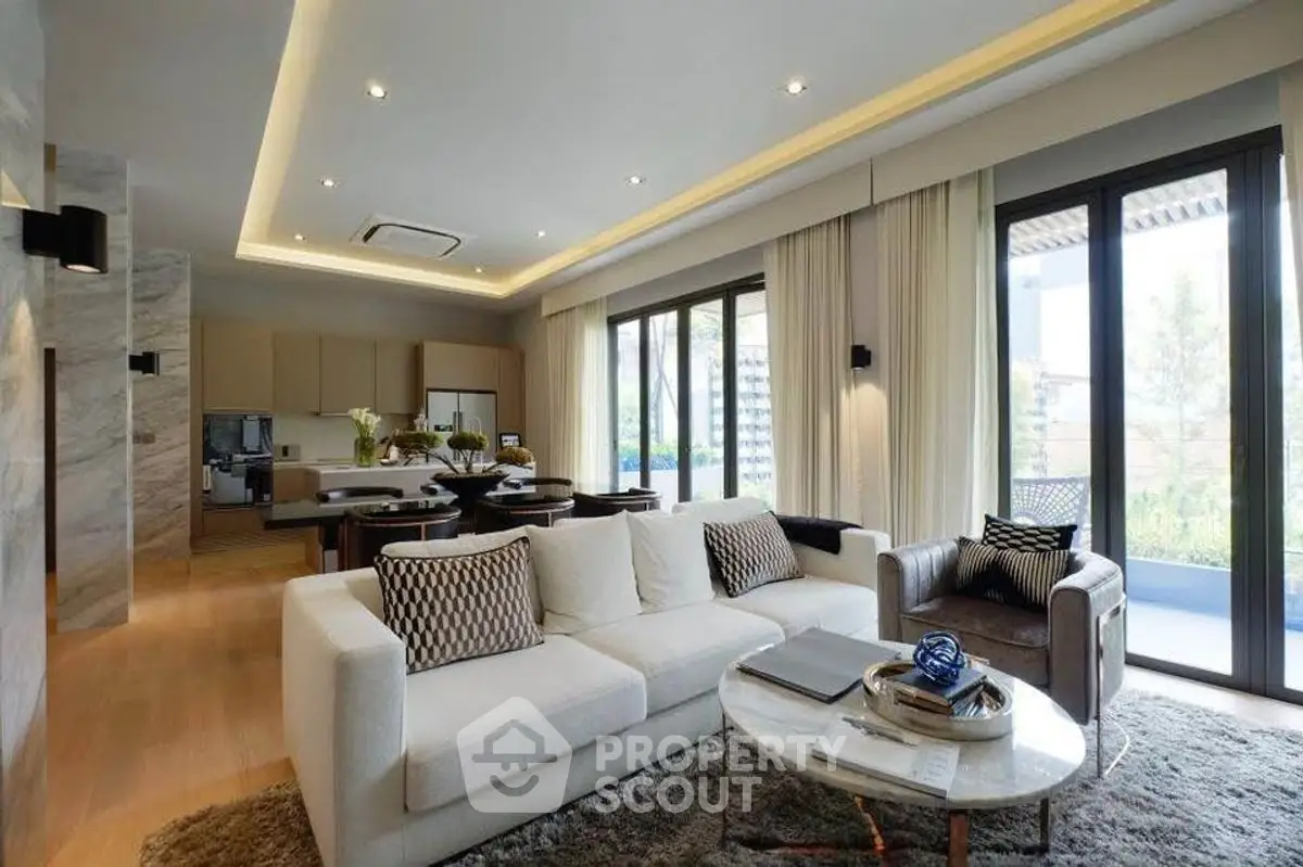 Luxurious open-plan living room with modern decor and large windows offering natural light and garden views.