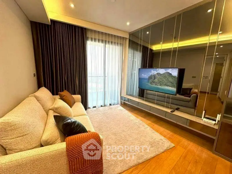 Modern living room with cozy sofa and large TV, featuring elegant decor and natural light.