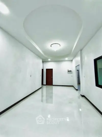 Spacious modern interior with sleek white walls and polished floors, featuring elegant ceiling design.