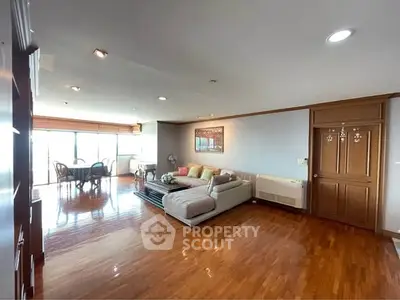 Spacious living room with wooden flooring and large windows offering natural light.