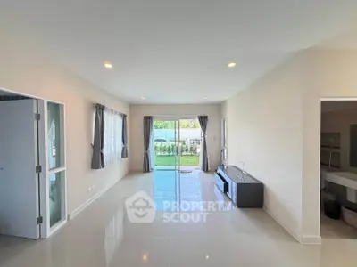 Spacious living room with large windows and garden view, perfect for family gatherings.