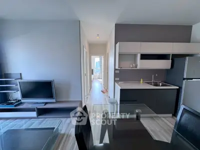 Modern open-plan living room with sleek kitchen and dining area, featuring contemporary furniture and appliances.