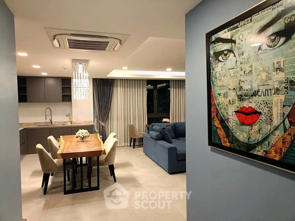 Modern open-plan living room with stylish dining area and contemporary art on the wall.
