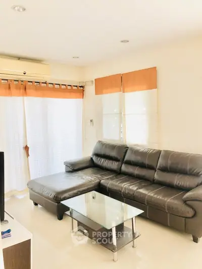 Spacious living room with modern leather sofa and glass coffee table, perfect for relaxation and entertainment.