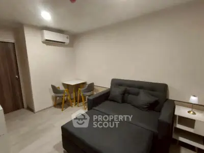 Cozy living room with modern sofa and dining area in compact apartment.