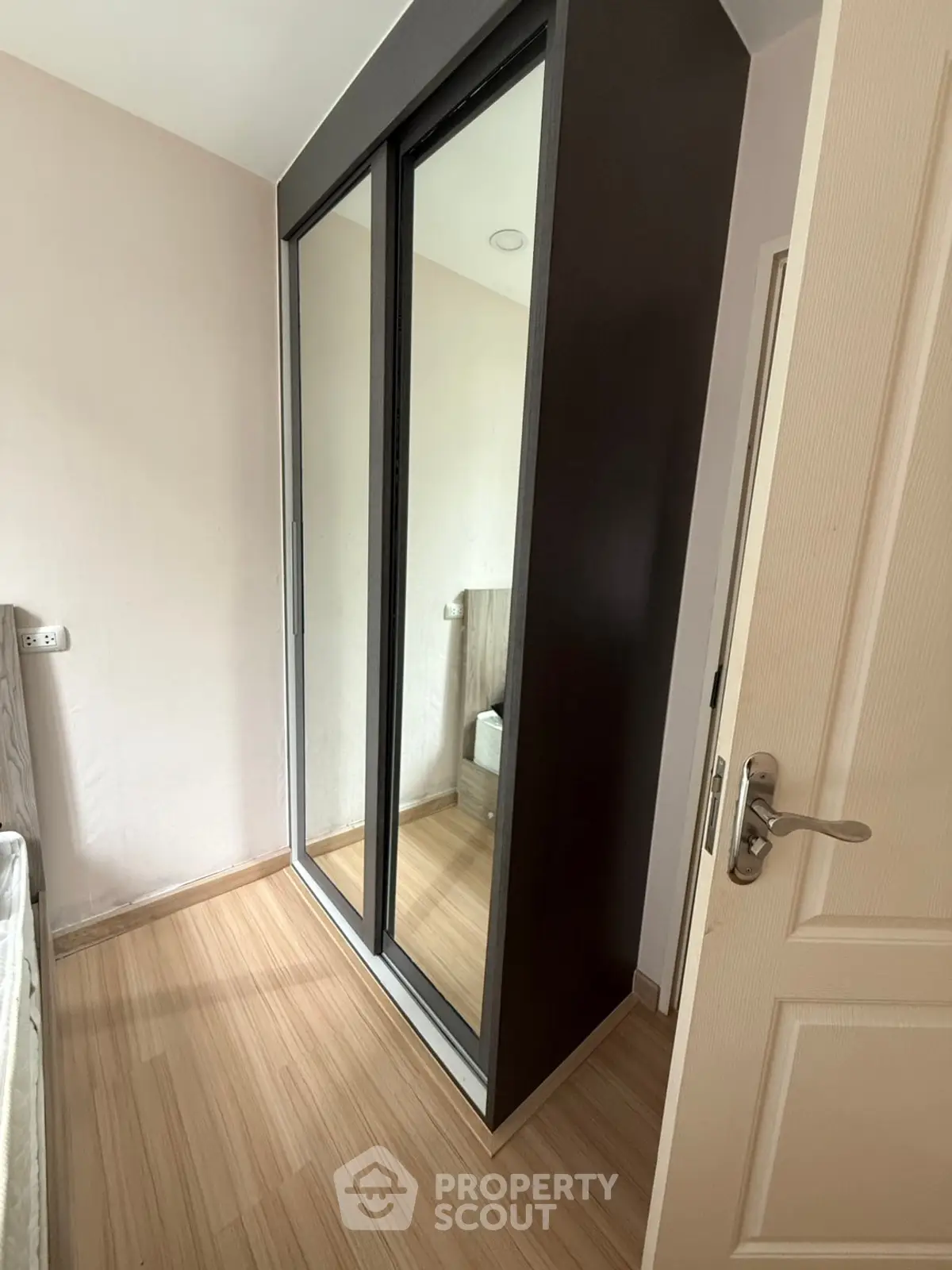 Modern bedroom with sleek mirrored wardrobe and wooden flooring