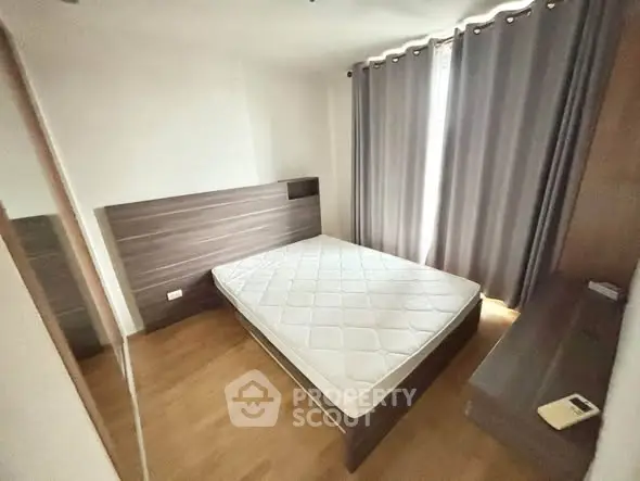 Spacious bedroom with modern design and natural light, featuring a comfortable bed and elegant curtains.