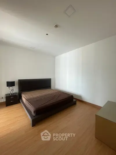 Spacious minimalist bedroom with wooden flooring and modern furniture