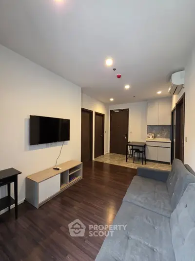 Modern living room with sleek furniture and open kitchen layout in a stylish apartment.