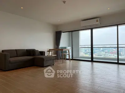 Spacious living room with city view and modern furnishings in high-rise apartment.