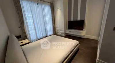 Elegant bedroom with modern decor and large window, featuring a sleek TV setup and stylish furnishings.