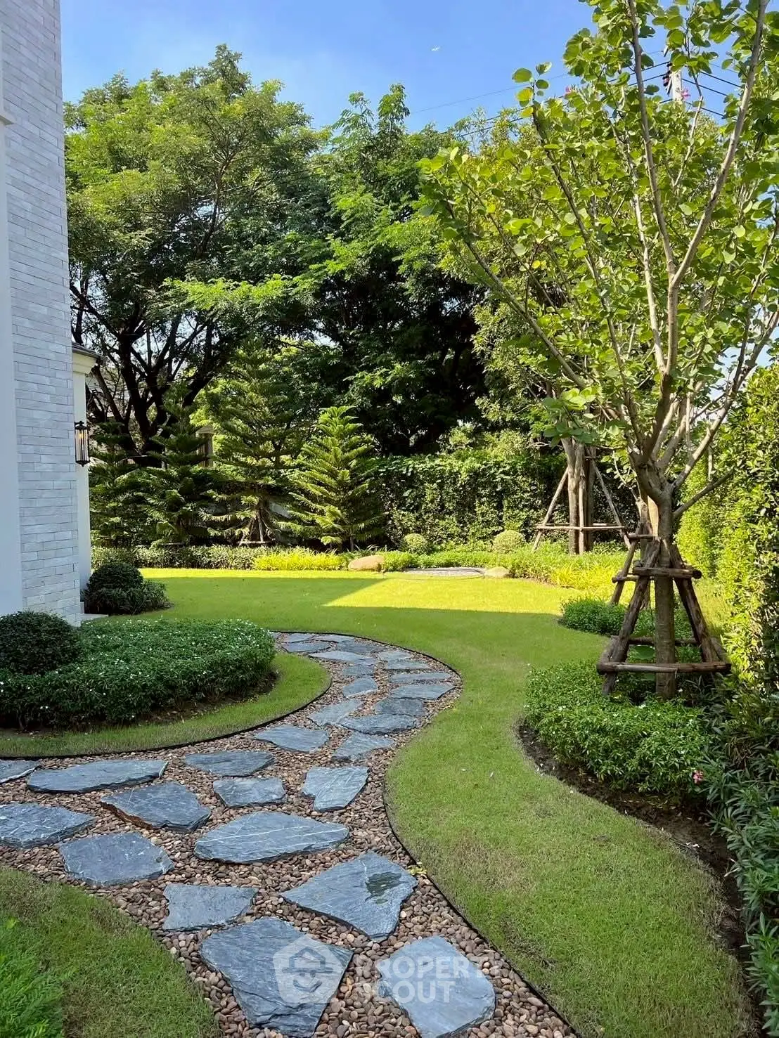Charming garden with stone pathway and lush greenery in a serene residential setting.