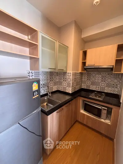 Modern compact kitchen with stylish backsplash and built-in appliances in cozy apartment.