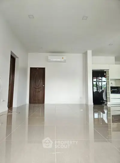 Spacious modern living room with glossy tiled floors and sleek kitchen appliances.