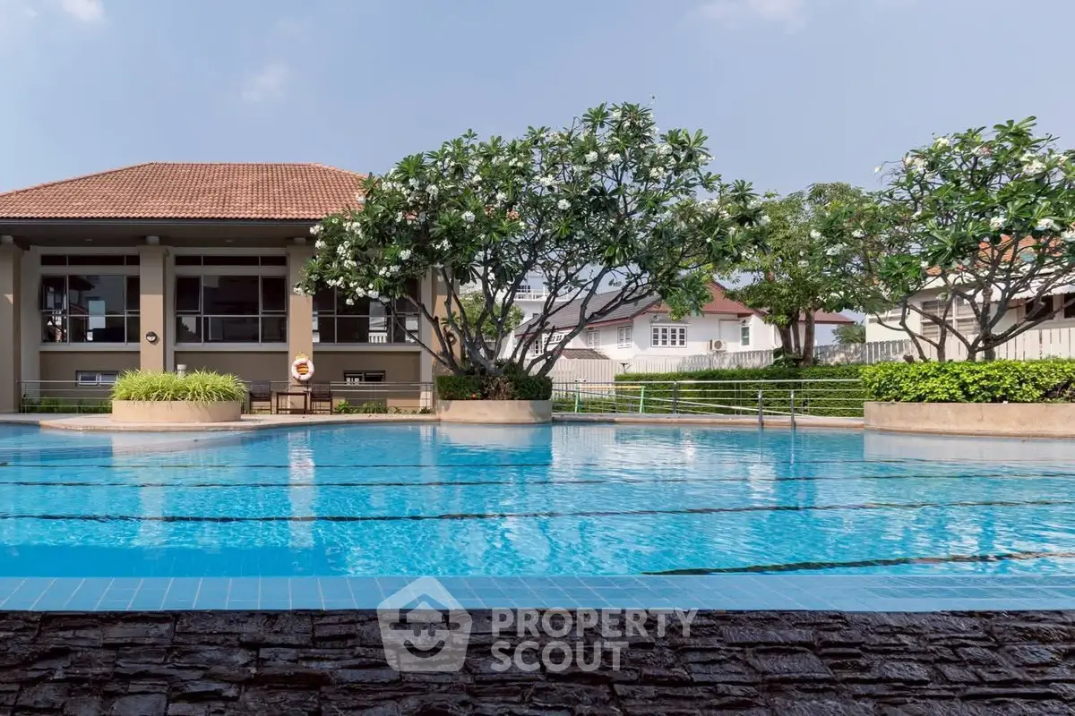 Luxurious residential pool area with lush greenery and elegant architecture.