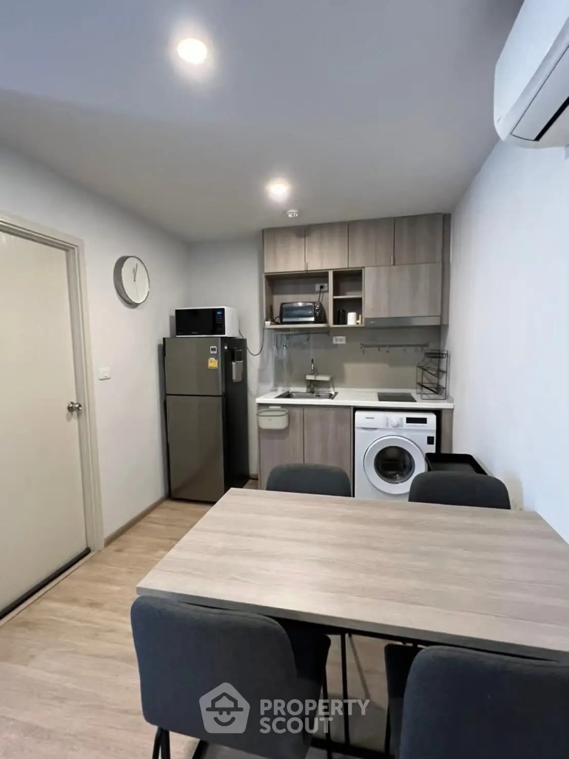 Modern kitchen with dining area, featuring washing machine and sleek appliances.