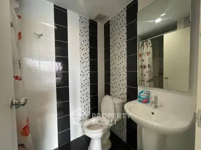 Modern bathroom with stylish black and white tiles, featuring a sleek sink and toilet.
