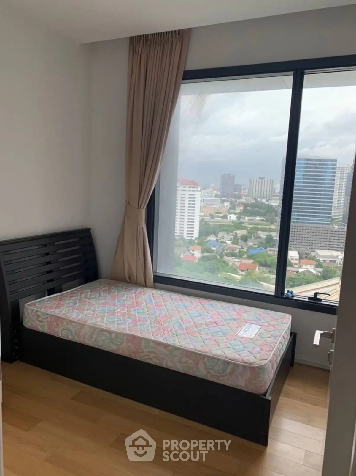 Cozy bedroom with single bed and panoramic city view from large window