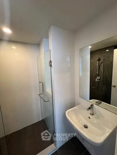 Modern bathroom with sleek shower and elegant sink in contemporary apartment.