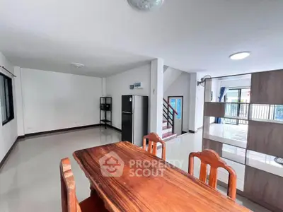 Spacious open-plan living area with wooden dining set and modern staircase