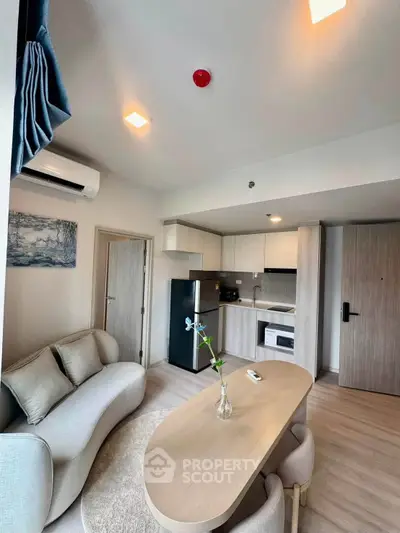 Modern living room with open kitchen, featuring sleek furniture and contemporary design.