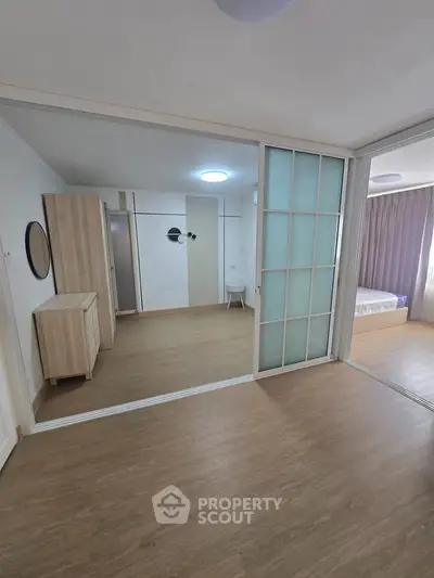 Spacious modern bedroom with sliding glass doors and wooden flooring.
