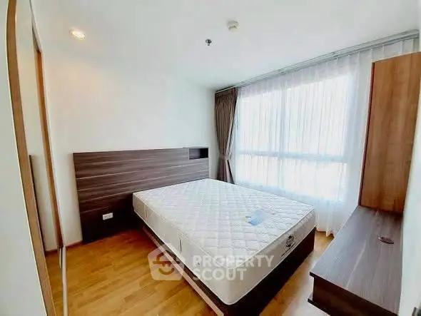 Spacious bedroom with large window and modern furnishings in a bright apartment.