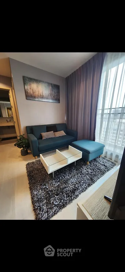 Modern living room with stylish sofa, cozy rug, and large window for natural light.