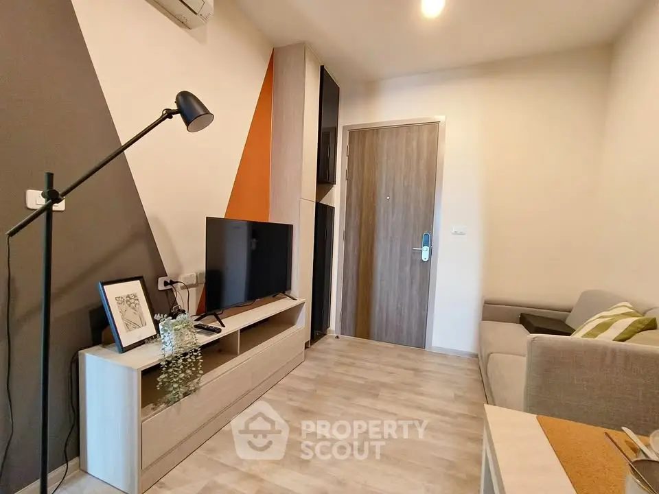 Modern living room with stylish decor and wooden flooring, featuring a cozy sofa and entertainment unit.