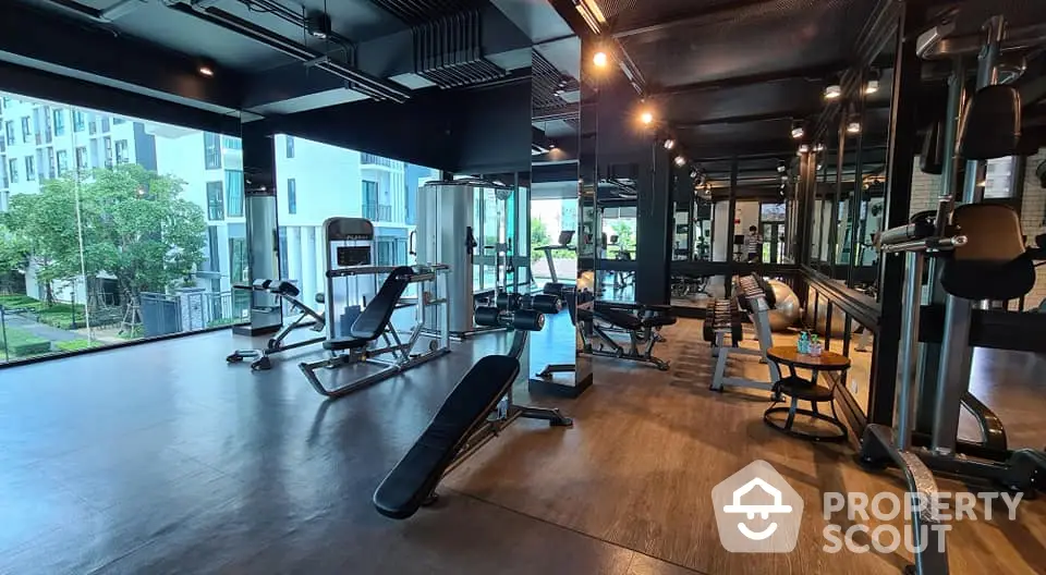 Modern gym with state-of-the-art equipment and large windows in luxury apartment complex.