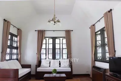 Charming living room with high ceiling and elegant windows, perfect for cozy gatherings.