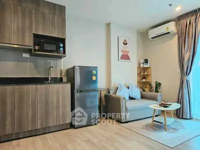 Modern living room with kitchenette, featuring sleek cabinetry, cozy sofa, and natural light.