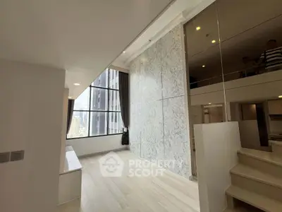 Modern loft apartment with large windows and stylish marble wall, offering a bright and spacious living area.