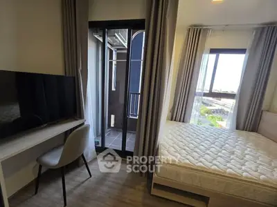 Modern bedroom with balcony access and natural light, featuring a sleek desk and flat-screen TV.
